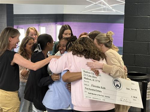 Group hug of teachers around a colleague